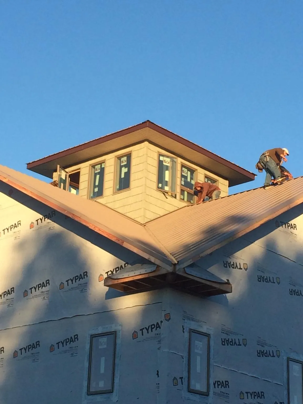 Roofers working around a rooftop cupola on a new metal roof at sunset — Roof Waterproofing in Potsdam by Roofing Brothers